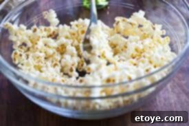 Fluffy popcorn ready for seasoning in a large mixing bowl