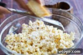 Adding grated Parmesan cheese to truffle oil popcorn