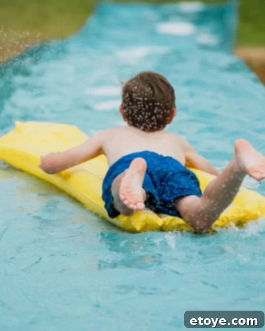 Epic Paddle Board Sweepstakes 4 Children happily playing on a homemade slip and slide in a backyard