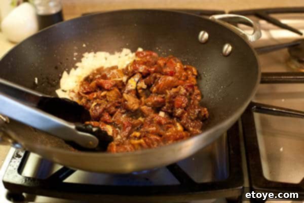 Bulgogi Rice Bowl 9 Marinated beef being stir-fried with onions in a wok