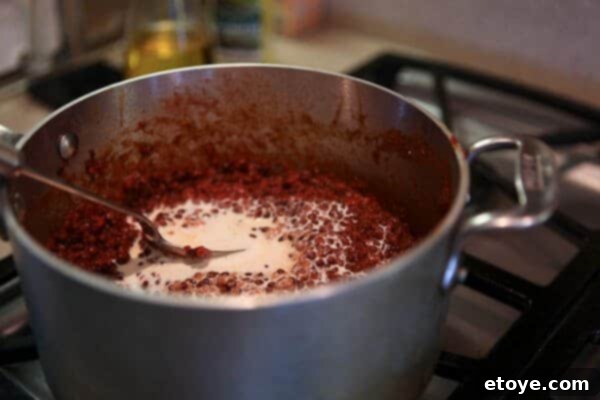 Indian Dal: Culinary Enlightenment 3 A hand carefully stirring a generous pour of heavy cream into the cooked lentil mixture, enriching the Dal Nirvana with a luxurious, velvety texture.