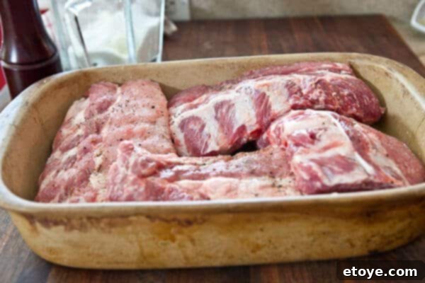 Fall-Off-The-Bone Sweet Chili Ribs 11 Side view of multiple racks of fall-off-the-bone baby back ribs layered in a roasting pan.