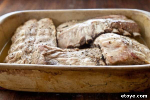 Fall-Off-The-Bone Sweet Chili Ribs 13 Cooked, roasted tender baby back ribs in a pan after 4 hours of slow cooking, showcasing their readiness for saucing.