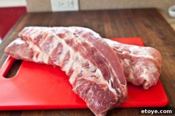Fall-Off-The-Bone Sweet Chili Ribs 3 Close-up of baby back ribs on a cutting board, highlighting the membrane on the bone side that needs to be removed for tenderness.