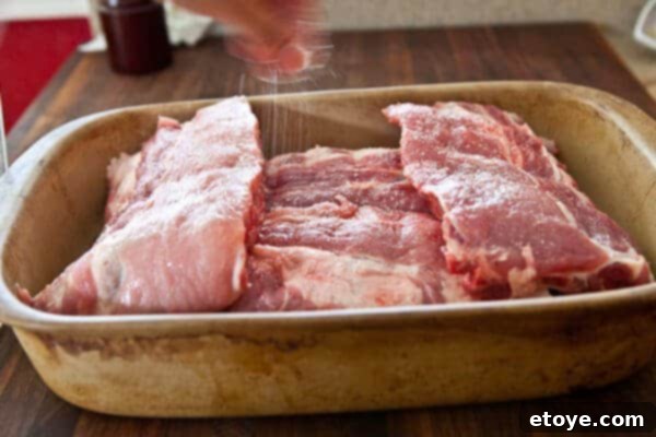Fall-Off-The-Bone Sweet Chili Ribs 9 Baby back ribs in a roasting pan being seasoned with salt on both sides prior to slow roasting.
