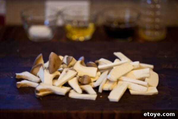 Sliced King Trumpet mushrooms being sautéed in a pan before adding teriyaki sauce