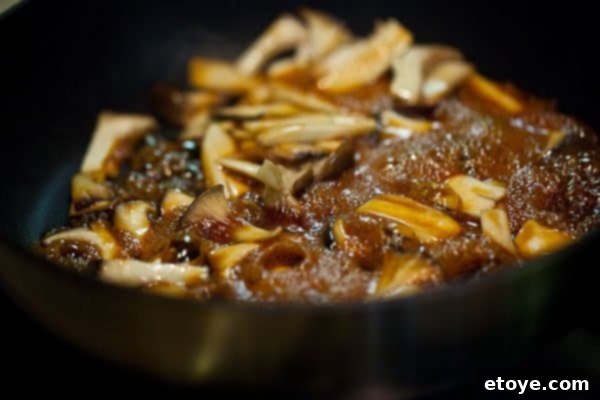 Finished plate of grilled salmon with teriyaki mushrooms, garnished with green onions