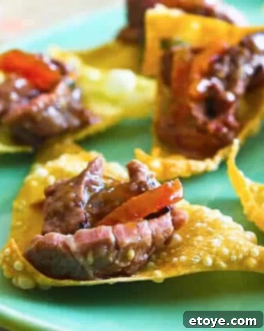 Korean BBQ Beef served elegantly on crispy wonton chips, garnished with fresh herbs and a side of apricot marmalade.