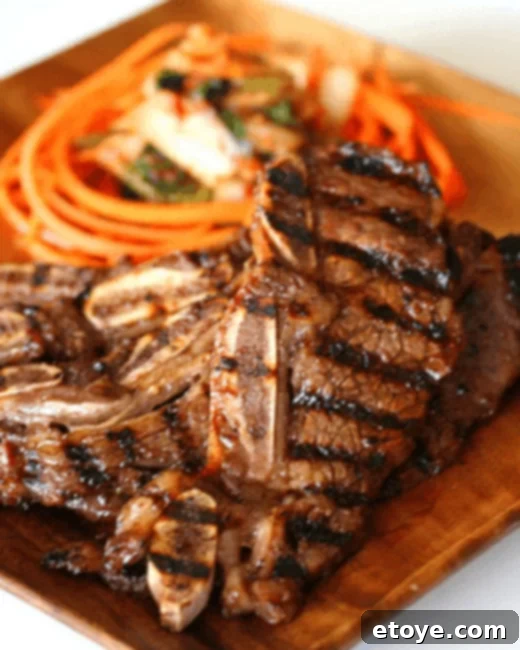 Assortment of marinated Kalbi short ribs and Bulgogi beef sizzling on an indoor tabletop grill during a Korean BBQ session.