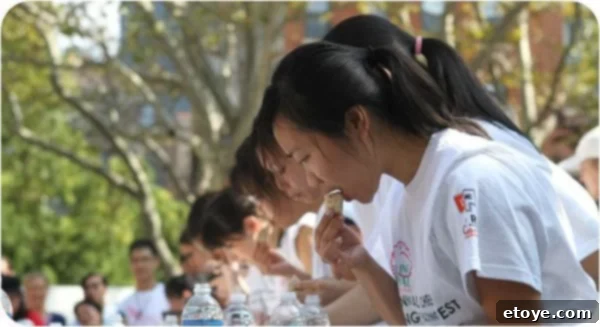 A focused female contestant showcasing her elegant yet rapid dumpling-eating strategy in close-up