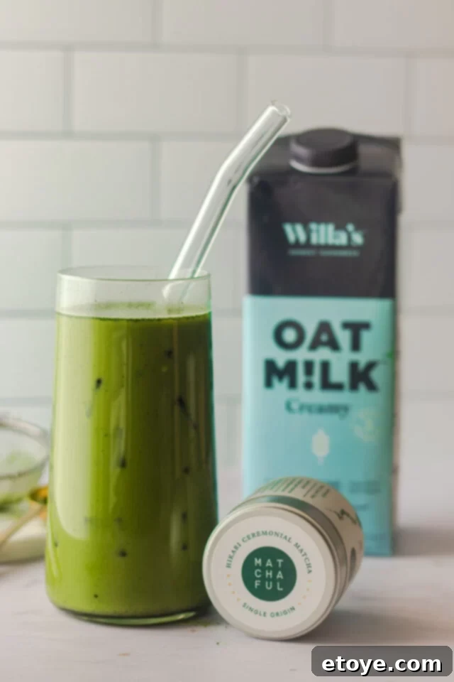 Close up shot of container of matcha green tea next to a glass of iced matcha.