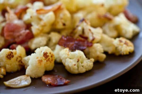 Roasted Cauliflower with Bacon and Garlic Recipe Delicious roasted cauliflower florets with crispy bacon bits and garlic on a serving plate