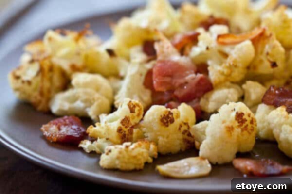 Roasted Cauliflower with Bacon and Garlic Recipe Crispy bacon pieces scattered over roasted cauliflower florets, ready to be served.