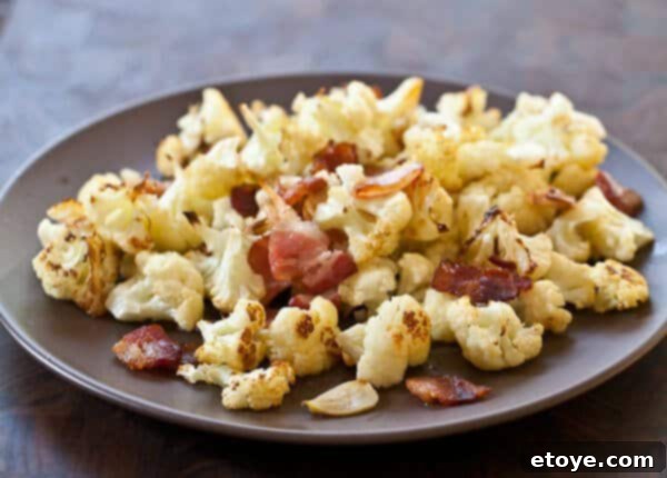 Roasted Cauliflower with Bacon and Garlic Recipe A dish of perfectly roasted cauliflower with golden-brown edges on a plate.