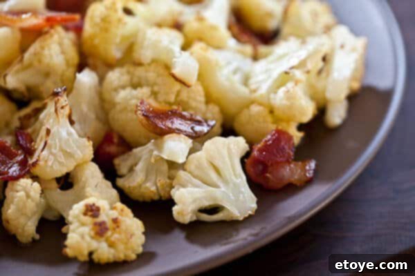 Roasted Cauliflower with Bacon and Garlic Close-Up Close-up view of perfectly roasted cauliflower with visible crispy bacon and garlic bits.