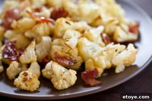 Roasted Cauliflower with Bacon and Garlic Served Roasted cauliflower with bacon and garlic served in a bowl, garnished.