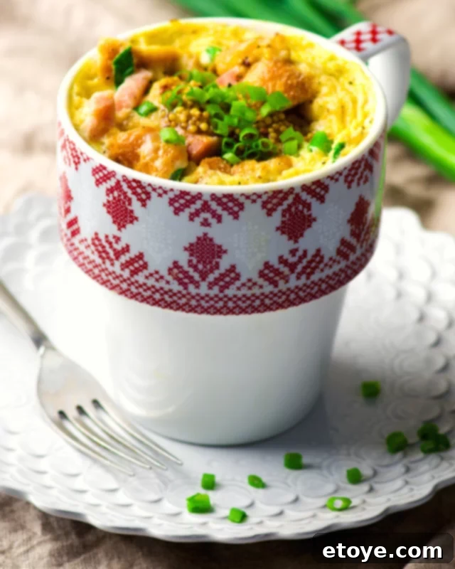 Quick-Fix Quiche Cup 4 Fluffy microwave quiche in a white mug, garnished with diced ham and fresh chives, a perfect quick breakfast.