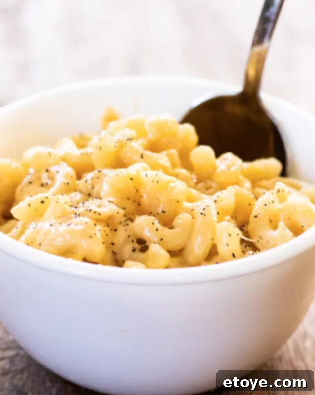 Close-up shot of a white bowl filled with incredibly creamy and rich mac and cheese, ready for serving.