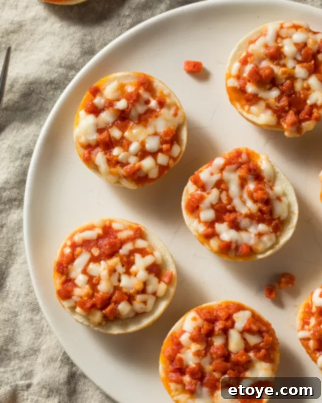 Pepperoni pizza bagel bites on a white plate, ready to be enjoyed.