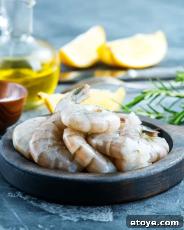 Garlic Shrimp in Minutes 5 Raw, unpeeled shrimp arranged on a clean white plate, ready for preparation.