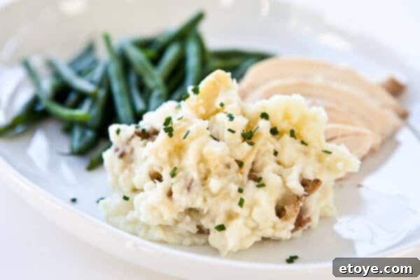 Perfectly Roasted Garlic Mashed Potatoes for the Holidays Roasted Garlic Mashed Potatoes on plate, garnished with fresh chives, ready to be served