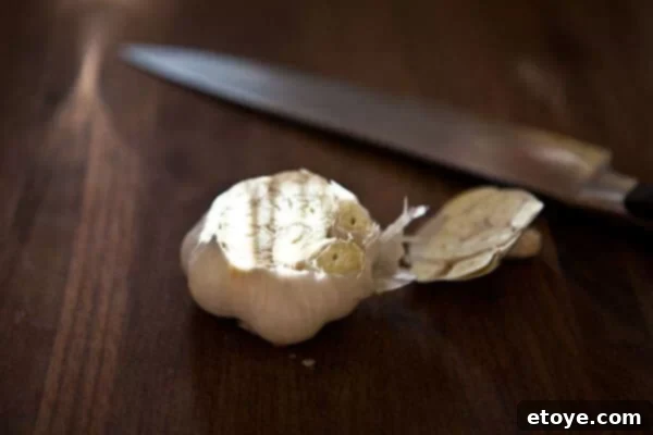 Garlic head prepared for roasting Close-up of a whole head of garlic with the top cut off, exposing the cloves