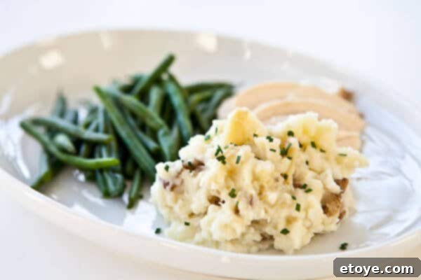 Serving suggestion for roasted garlic mashed potatoes Roasted Garlic Mashed Potatoes served with green beans on a plate, ready to enjoy