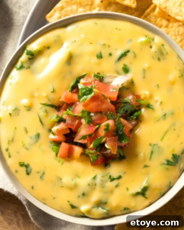 Quick Microwave Queso Dip 4 An inviting, close-up shot of creamy, golden queso dip in a white ceramic bowl, showcasing its smooth texture and readiness to be enjoyed.