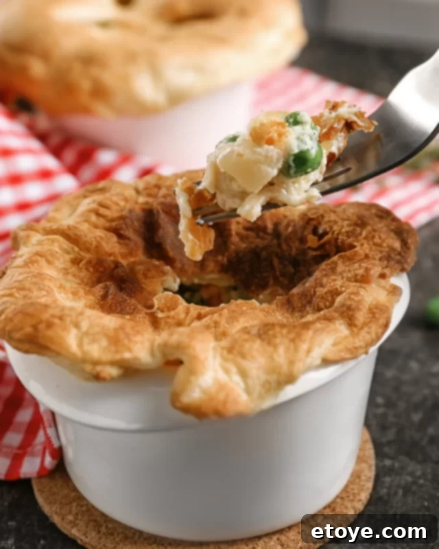 Fork digging into a baked chicken pot pie in a mug.