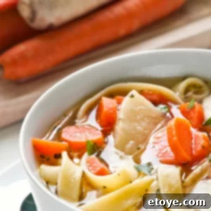Up close photo of chicken noodle soup with carrots and noodles.