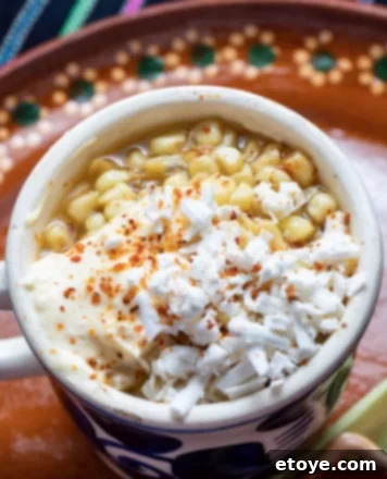Elote corn served in a mug on a red plate, ready to be enjoyed.