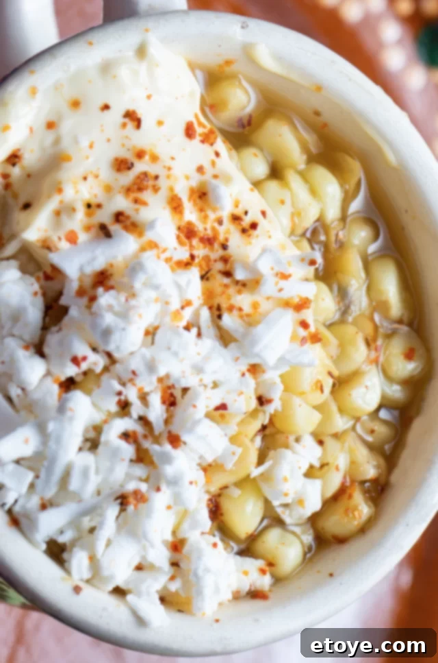 Close-up shot of Elote with chili flakes on top, highlighting the creamy texture and vibrant spices.