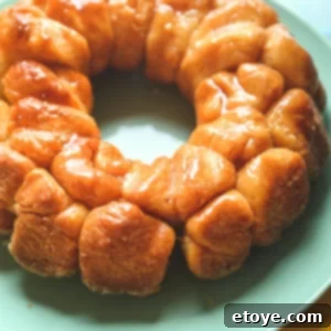 Monkey bread with butter and cinnamon sugar over the top on a green plate.