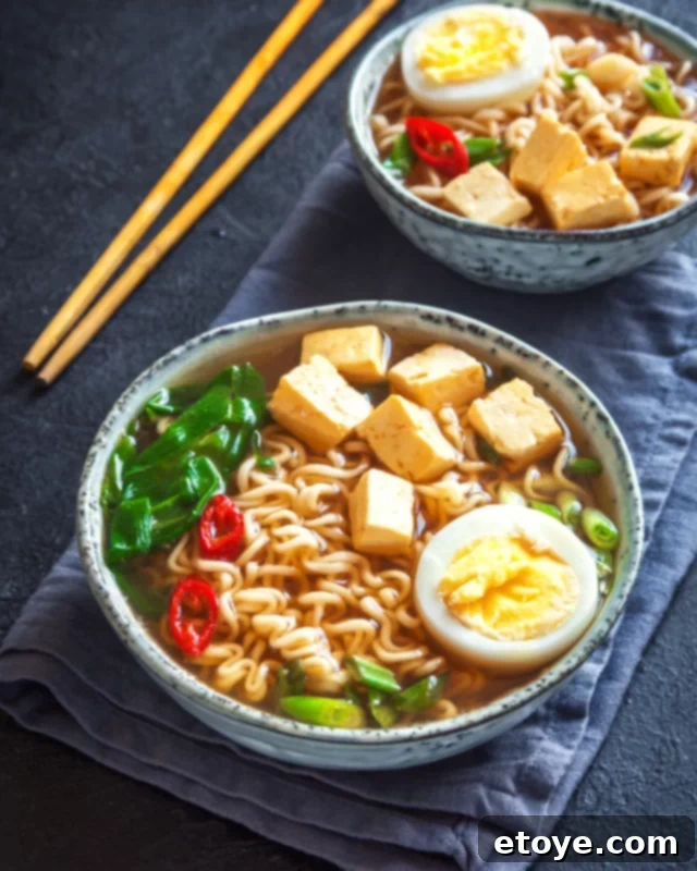 Elevate Your Microwave Ramen 2 A vibrant bowl of ramen noodle soup, garnished with a perfectly soft-boiled egg, fresh green onions, and fiery red chili threads, ready to be enjoyed.