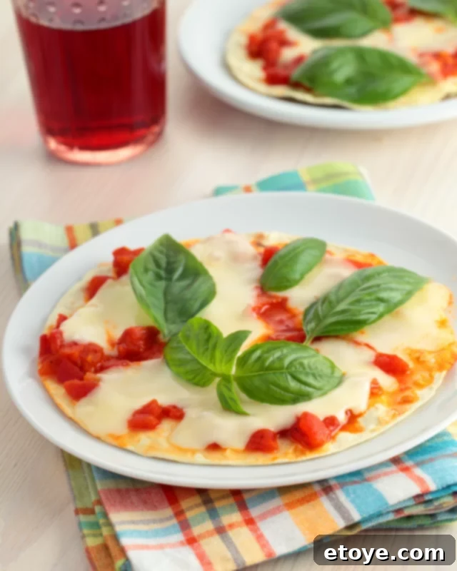 Freshly made tortilla pizza with mozzarella and basil on a white plate, ready to be eaten.