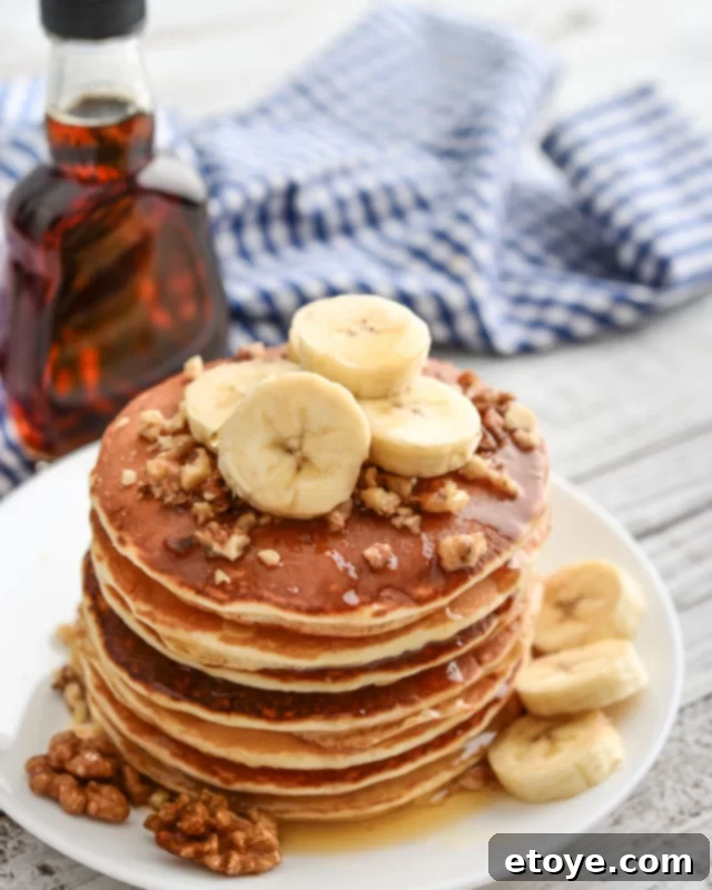 Microwave Pancakes: Quick and Easy Delights 4 Pancakes stacked with fresh banana slices and chopped walnuts on a white plate, ready for breakfast.