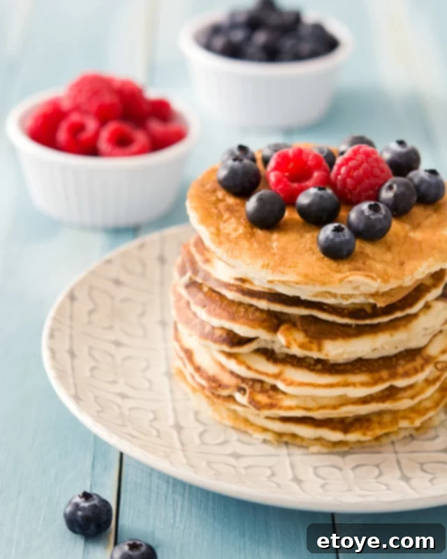 Microwave Pancakes: Quick and Easy Delights 5 Stacked microwave pancakes with an abundance of fresh blueberries and raspberries on top.