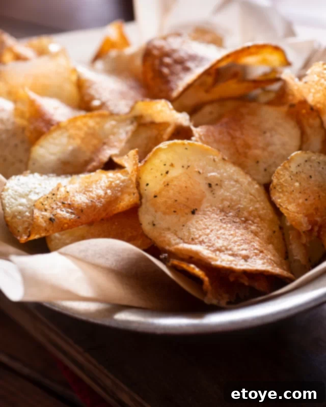 Potato chips on parchment paper in a big bowl.