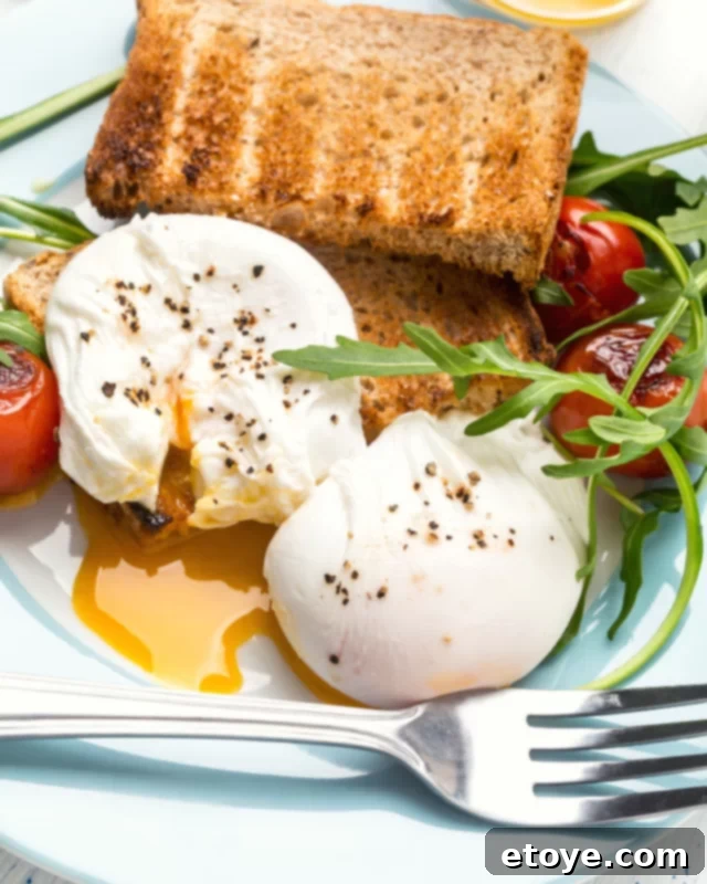 Easy Microwave Poached Eggs 5 Two close-up poached eggs, seasoned with salt and pepper, highlighting their firm whites and ready-to-burst yolks, perfect for any dish.