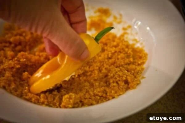 Crispy Baked Jalapeno Bacon Poppers 11 A spoonful of melted butter being mixed into a bowl of corn flake crumbs.