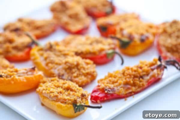 Crispy Baked Jalapeno Bacon Poppers 14 Two hands reaching for freshly baked sweet mini pepper poppers from a serving dish.