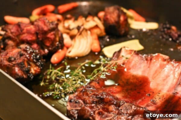 Ingredients for red wine jus simmering in the roasting pan.