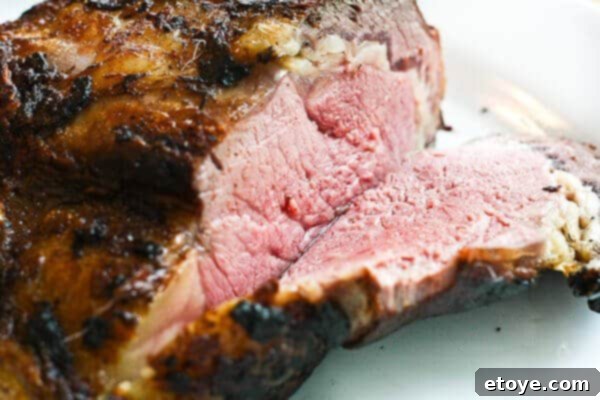 Expertly carving the perfectly cooked prime rib roast into individual slices.