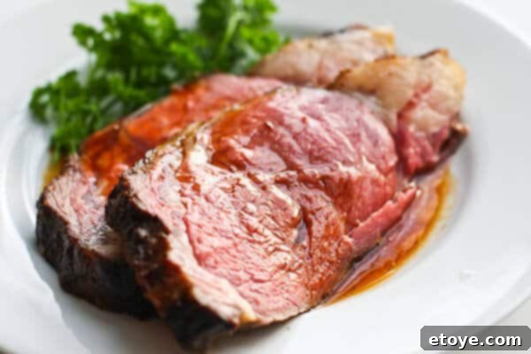 Perfectly cooked medium-rare prime rib on a plate, garnished and ready to serve.