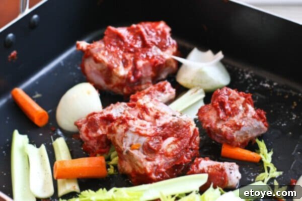 Roasting oxtail bones and vegetables with tomato paste for a flavorful jus base.