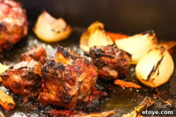 Roasted oxtail and vegetables in a pan, showcasing their caramelized goodness.