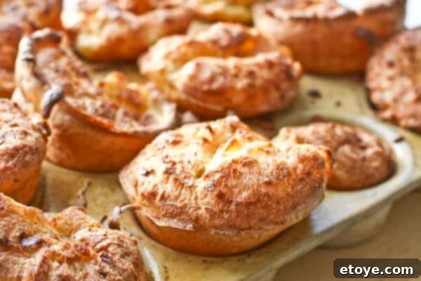 Close-up of freshly baked Yorkshire Puddings on a serving plate, showcasing their perfect rise and golden crust.