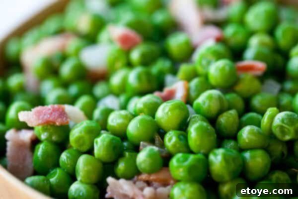 Crispy Bacon and Sweet Peas 2 Crispy bacon and vibrant green peas mixed with sautéed onions, ready to be served.