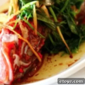 Chinese Steamed Fish garnished with fresh herbs, ready to be served.