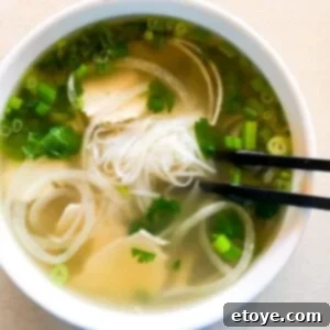 chicken pho in a white bowl with chopsticks